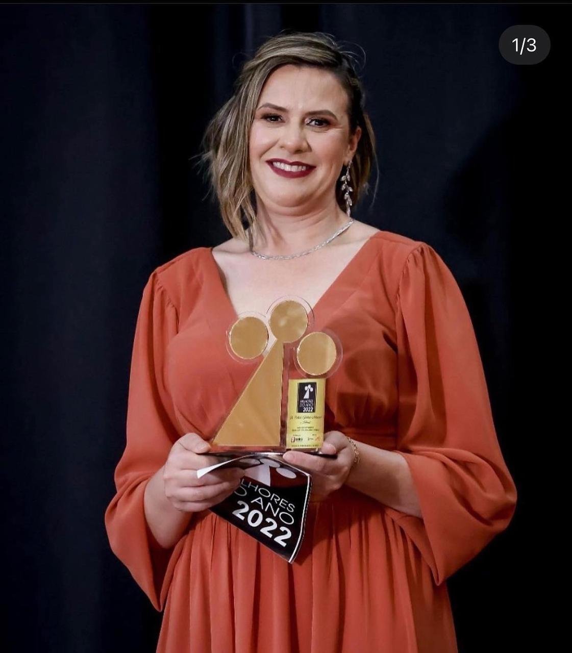 Fundadora da Di Piallato segurando o troféu de reconhecimento